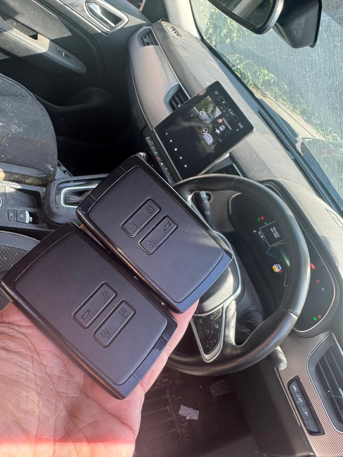 Renault key cards held inside a vehicle, with the dashboard mid-way through the key programming sequence